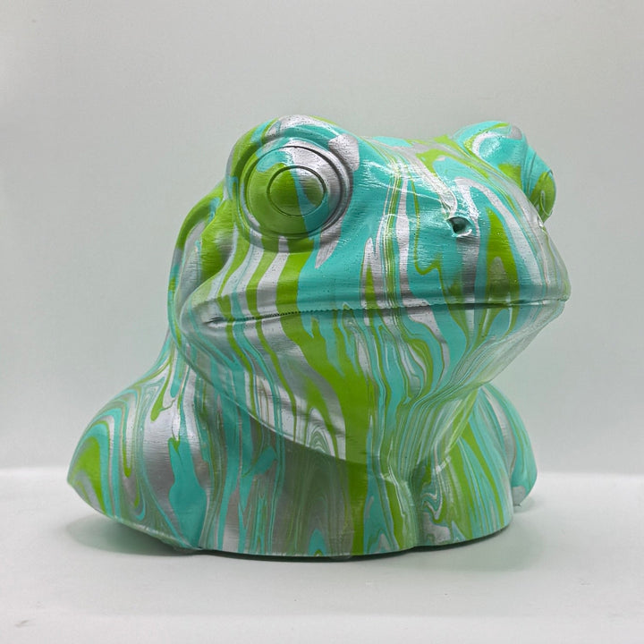 Three-quarter view of a turquoise, lime green and silver frog sculpture