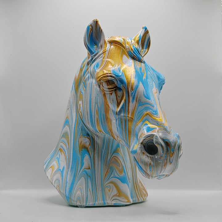 Angled view of a hand-painted horse head ornament with blue, white and gold marbling